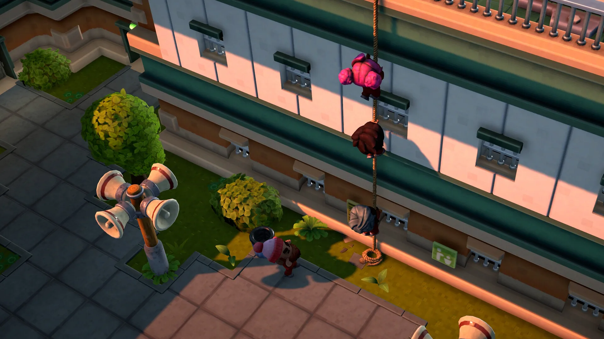 Official The Escapists 3 screenshot showing an outdoor prison area with a cream-colored building with barred windows and green trim